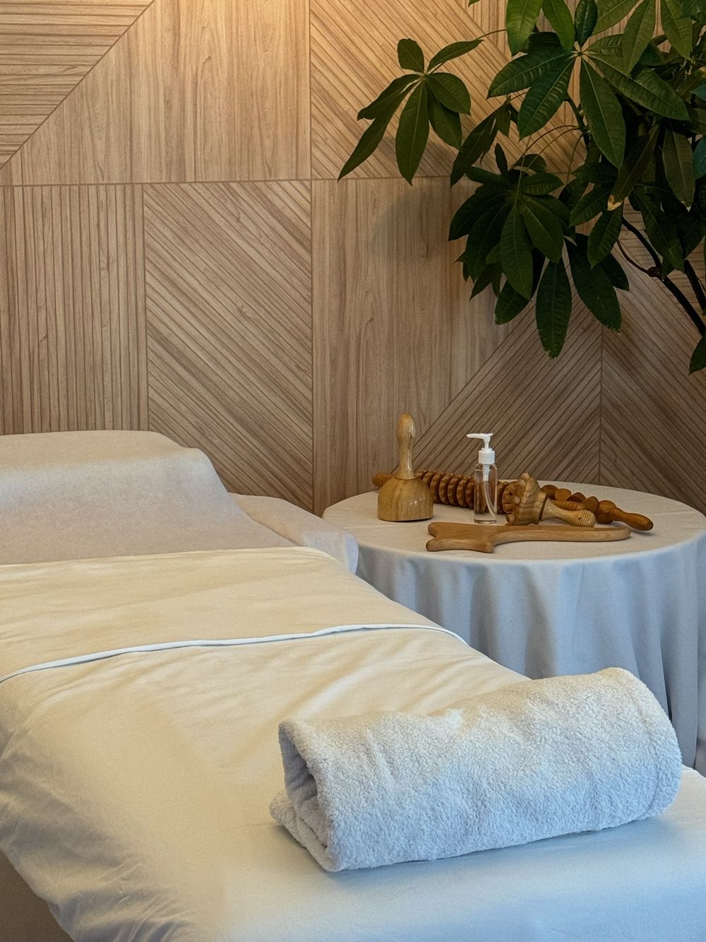 Le cabinet de Sonia à Suresnes : table de massage, serviette roulée et outils de madérothérapie en bois